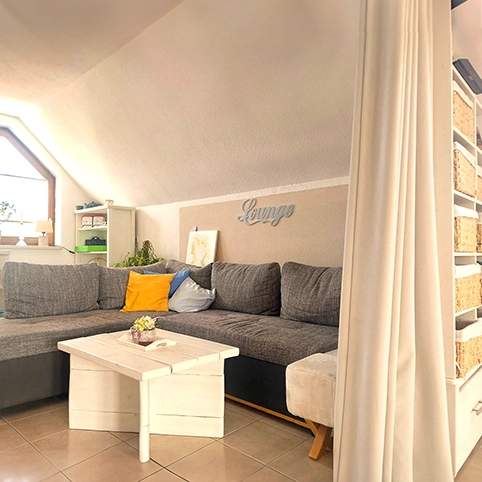 Lounge Loungebereich mit grauem Sofa abgetrennt von einem weißen Vorhang